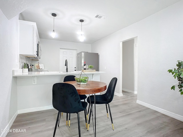 dining area featuring light wood-type flooring and sink