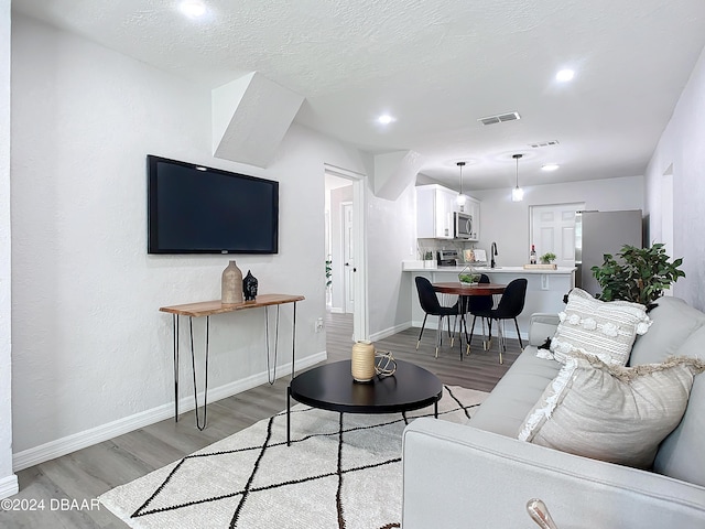 living room featuring sink, a textured ceiling, and light wood-type flooring