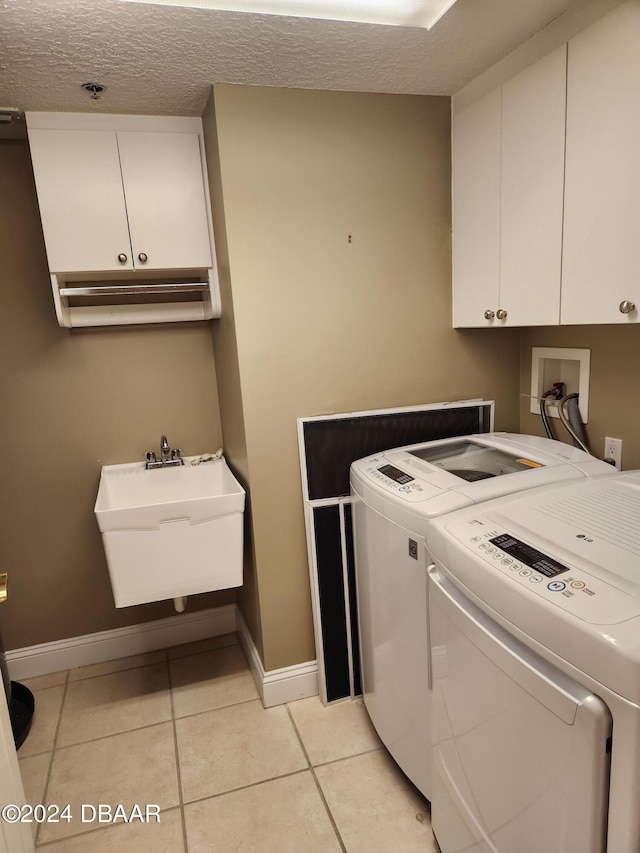 washroom featuring cabinets, a textured ceiling, light tile patterned floors, sink, and washer and dryer