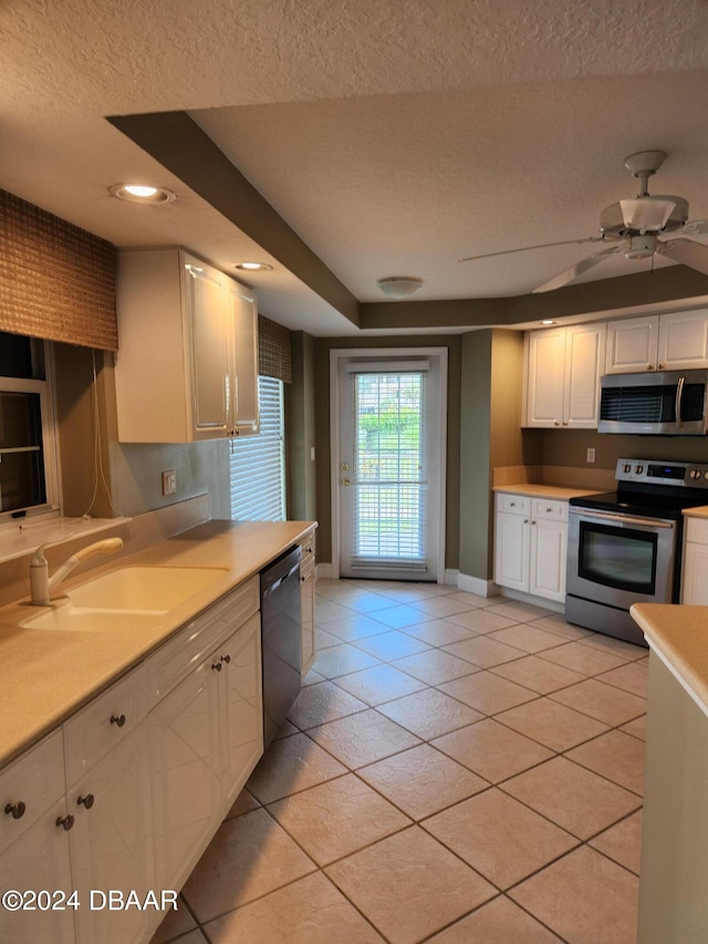 kitchen featuring stainless steel appliances, a textured ceiling, sink, light tile patterned floors, and white cabinetry