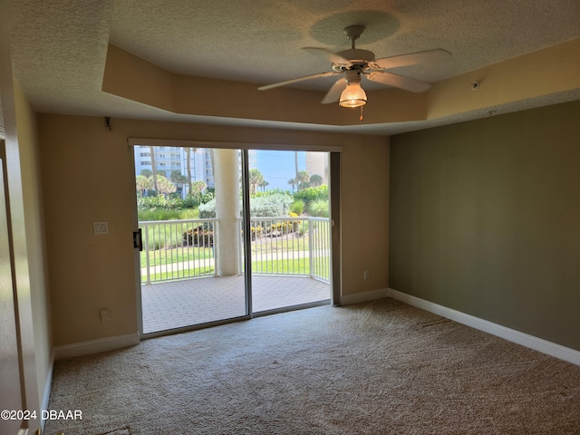 carpeted spare room featuring a raised ceiling, a textured ceiling, and ceiling fan