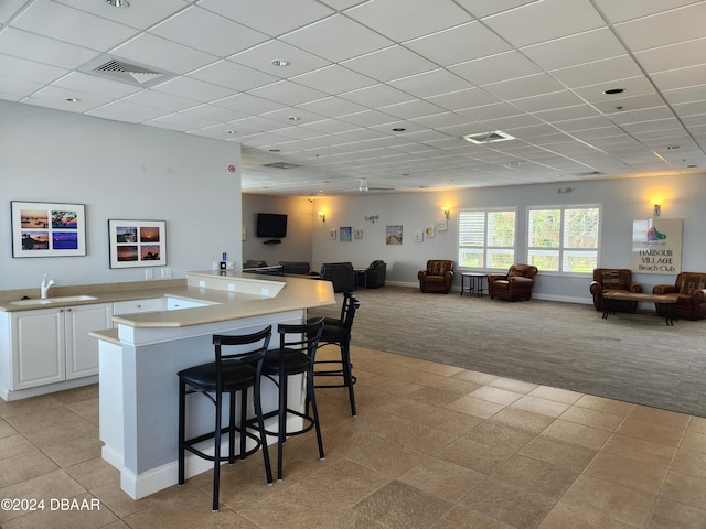 kitchen with white cabinetry, light carpet, sink, a breakfast bar area, and kitchen peninsula