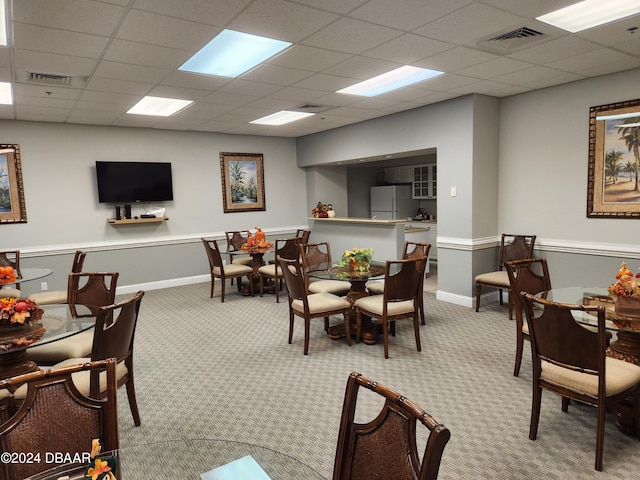 carpeted dining area with a drop ceiling