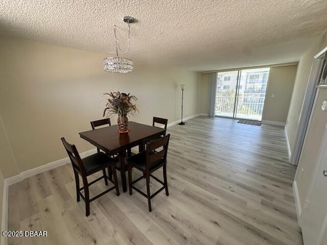 dining area featuring a textured ceiling, light wood-style floors, and an inviting chandelier