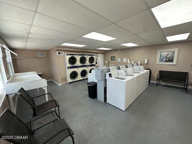 shared laundry area with baseboards, visible vents, stacked washer and clothes dryer, and washer and clothes dryer