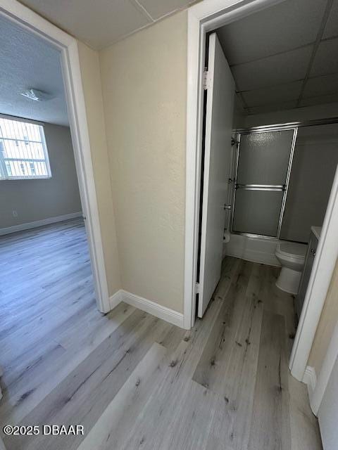 full bathroom with baseboards, toilet, and wood finished floors