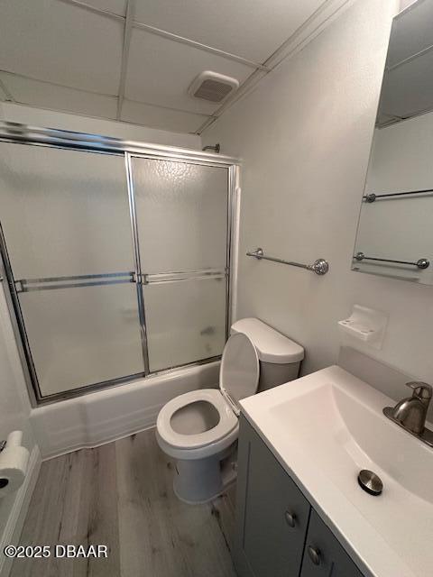 full bathroom featuring visible vents, bath / shower combo with glass door, toilet, wood finished floors, and vanity