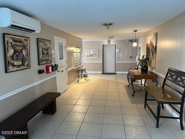 hall featuring light tile patterned flooring, a wall mounted AC, and baseboards