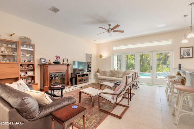 living room with ceiling fan, a textured ceiling, and light tile patterned floors