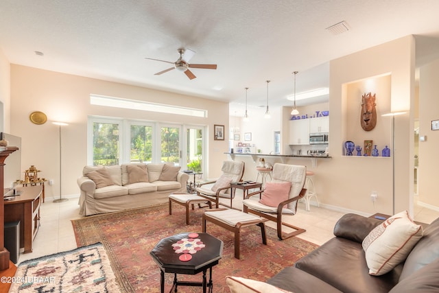 living room with ceiling fan, a textured ceiling, and light tile patterned floors