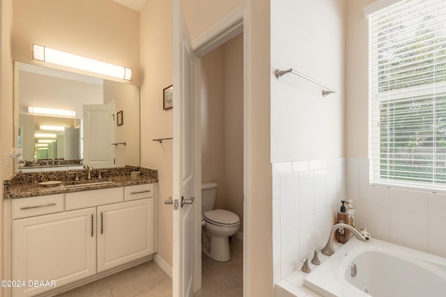 bathroom with tile patterned flooring, vanity, a relaxing tiled tub, and toilet