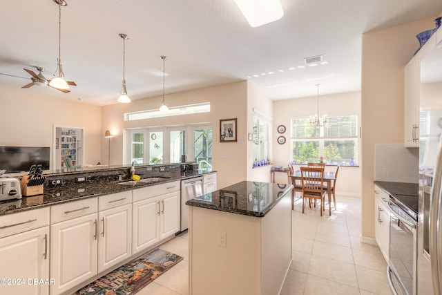 kitchen with sink, hanging light fixtures, dark stone countertops, appliances with stainless steel finishes, and white cabinets