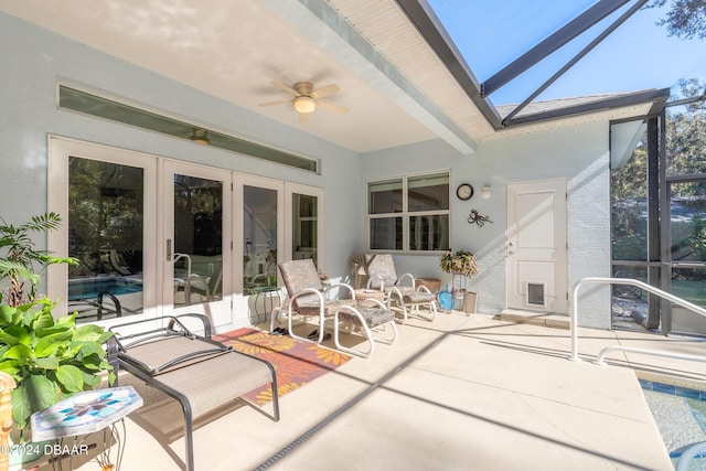 sunroom with beamed ceiling, ceiling fan, a skylight, and french doors