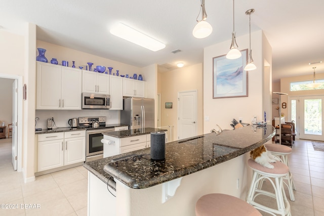 kitchen featuring appliances with stainless steel finishes, a breakfast bar, pendant lighting, sink, and white cabinets