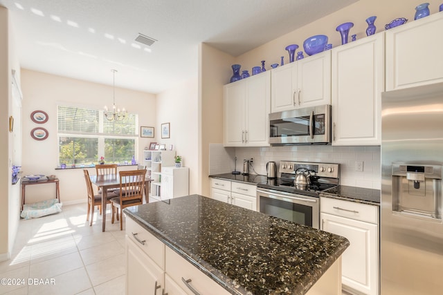 kitchen featuring stainless steel appliances, tasteful backsplash, a center island, and white cabinets