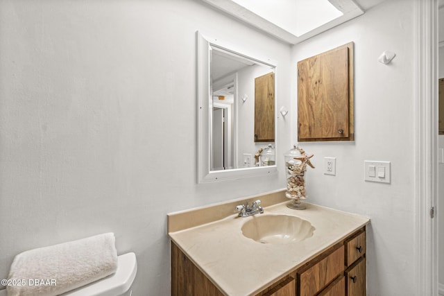 bathroom featuring vanity, toilet, and a skylight