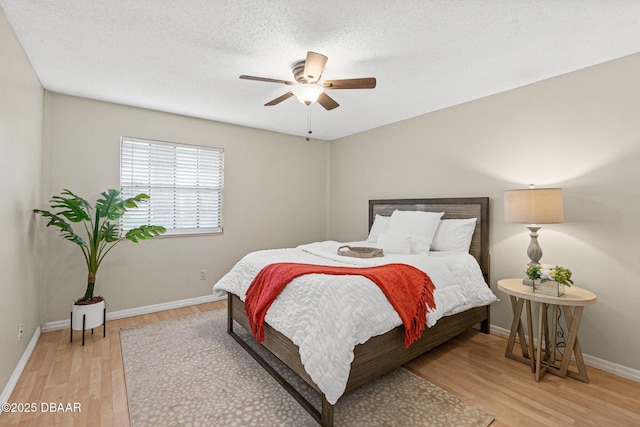 bedroom featuring ceiling fan, light hardwood / wood-style flooring, and a textured ceiling