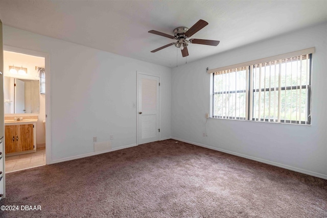 unfurnished bedroom featuring ensuite bathroom, ceiling fan, light carpet, and a closet