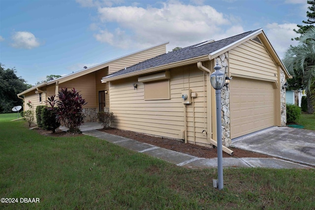 view of side of property featuring a garage and a lawn