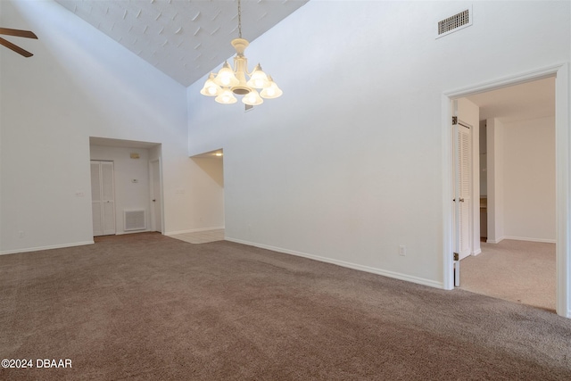 unfurnished living room featuring ceiling fan with notable chandelier, high vaulted ceiling, and carpet