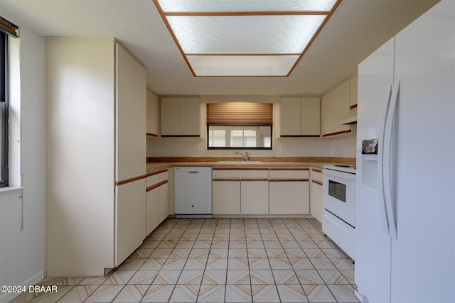 kitchen featuring white appliances, sink, light tile patterned flooring, and white cabinets