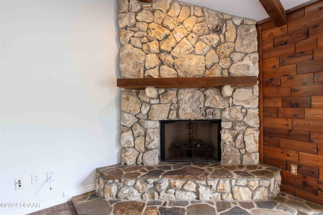 details with a stone fireplace and beam ceiling