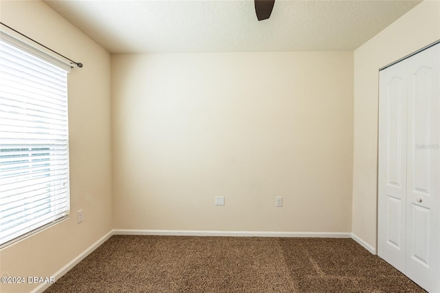 unfurnished bedroom featuring a closet, a textured ceiling, carpet flooring, and ceiling fan