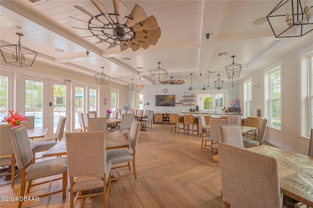 dining area featuring beamed ceiling, a wealth of natural light, ceiling fan, and light parquet floors