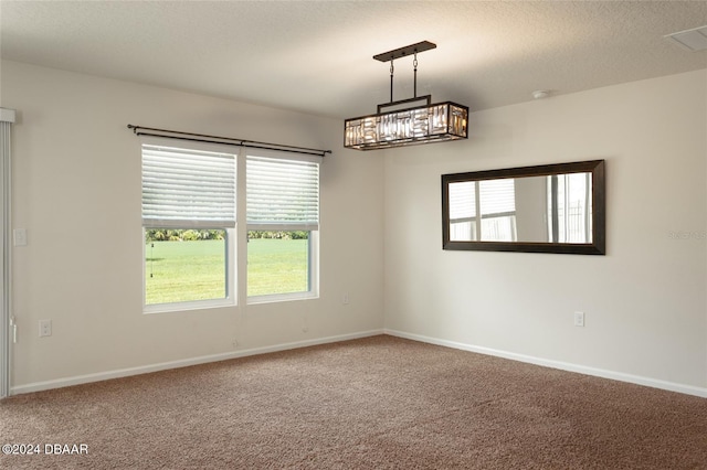 unfurnished room with a chandelier, a textured ceiling, and carpet floors