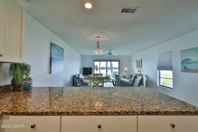 kitchen featuring dark stone counters, ceiling fan, and a textured ceiling