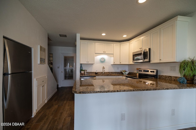 kitchen featuring stainless steel appliances, white cabinets, dark wood-type flooring, and kitchen peninsula