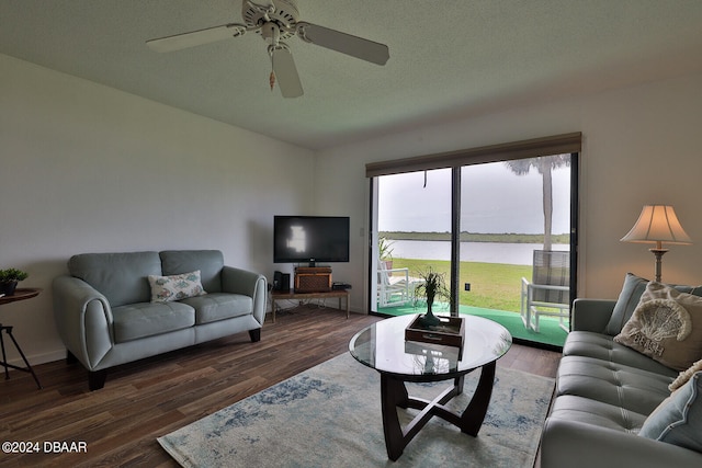 living room with dark wood-type flooring, ceiling fan, and a textured ceiling