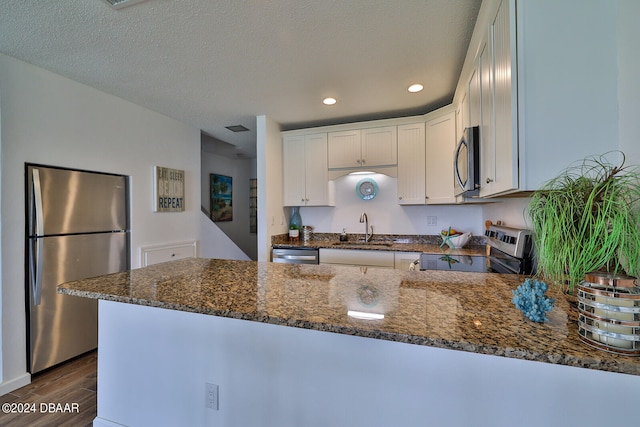 kitchen featuring stainless steel appliances, white cabinets, sink, dark hardwood / wood-style floors, and dark stone countertops