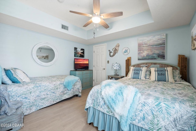 bedroom featuring ceiling fan, a raised ceiling, and wood-type flooring