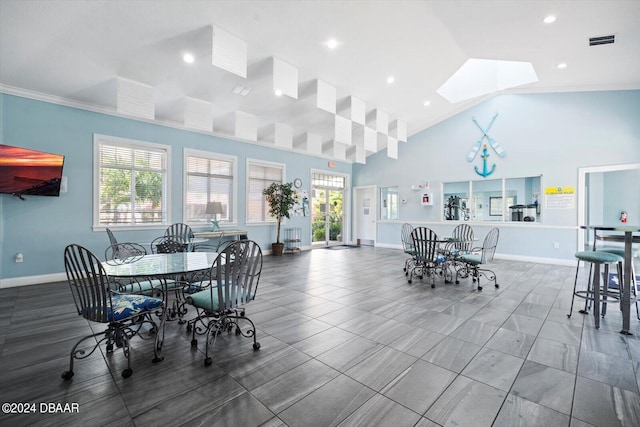 dining area with crown molding, high vaulted ceiling, and a skylight