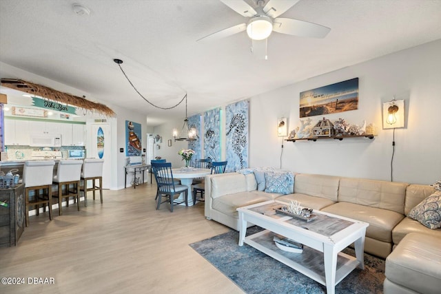 living room featuring light hardwood / wood-style floors and ceiling fan with notable chandelier