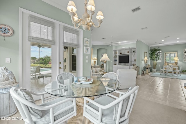 tiled dining space with built in features, a healthy amount of sunlight, ceiling fan with notable chandelier, and ornamental molding