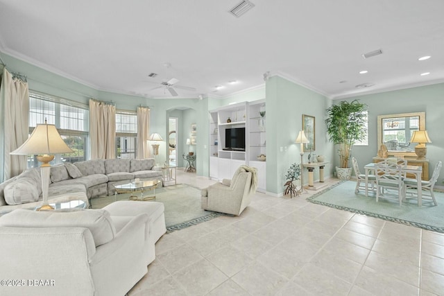 living room with built in shelves, light tile patterned floors, ceiling fan, and ornamental molding