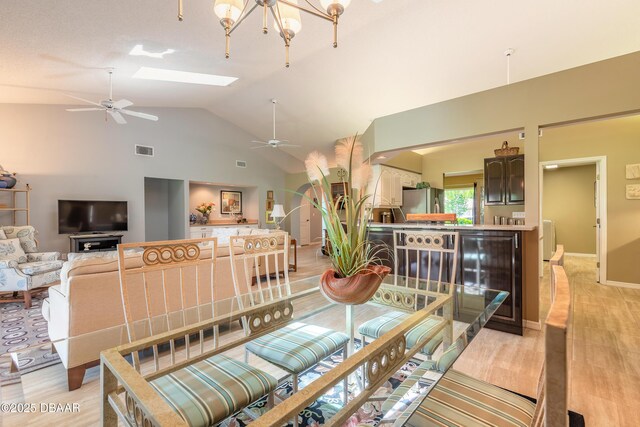 6273 Paradise Island Ct, Port Orange, FL 32128 - dining space with a ceiling fan, beverage cooler, a skylight, high vaulted ceiling, and light wood finished floors