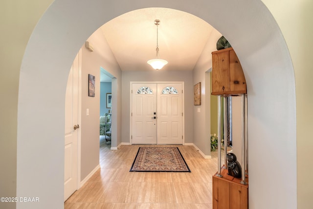 6273 Paradise Island Ct, Port Orange, FL 32128 - entryway featuring arched walkways, baseboards, lofted ceiling, and light wood-type flooring