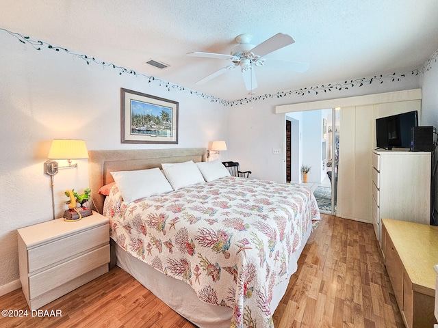 bedroom featuring ceiling fan, a textured ceiling, and light wood-type flooring