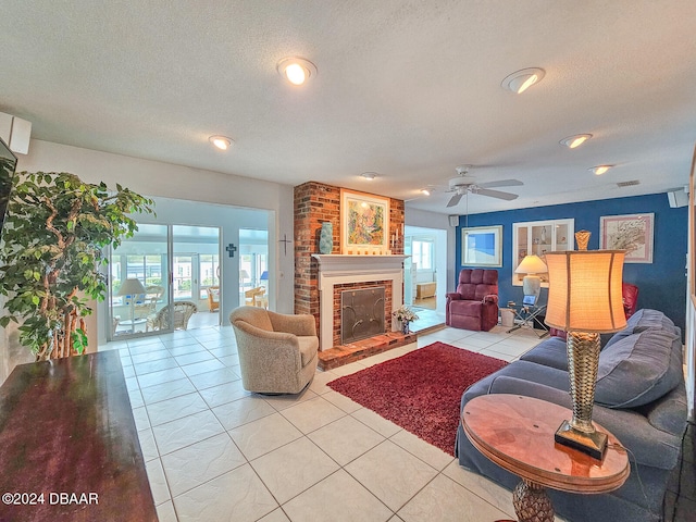 living room featuring ceiling fan, light tile patterned floors, a textured ceiling, and a brick fireplace