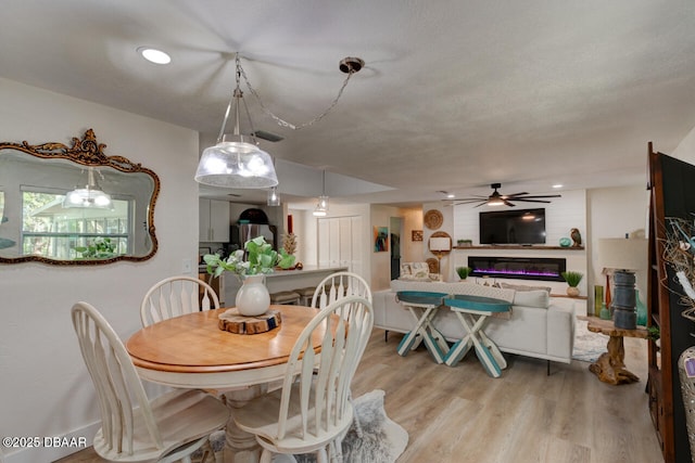 22 Cedar St, Port Orange, FL 32127 - dining room with ceiling fan, light wood-style flooring, and a glass covered fireplace