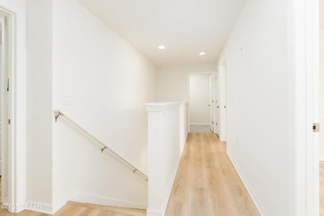hallway featuring an upstairs landing, light wood finished floors, recessed lighting, and baseboards