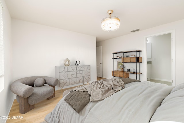 bedroom with baseboards, a chandelier, and light wood-type flooring