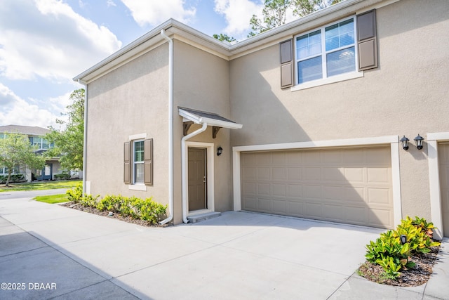 view of front of house with stucco siding, an attached garage, and driveway