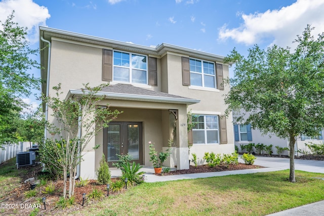 view of front of property featuring french doors, stucco siding, a front lawn, and central air condition unit