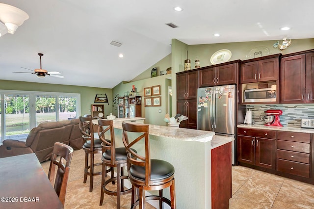 5479 Saint Regis Way, Port Orange, FL 32128 - kitchen featuring appliances with stainless steel finishes, vaulted ceiling, a breakfast bar area, tasteful backsplash, and recessed lighting