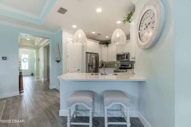 kitchen with sink, white cabinetry, stainless steel appliances, decorative light fixtures, and a raised ceiling