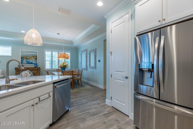 kitchen with sink, appliances with stainless steel finishes, hanging light fixtures, light hardwood / wood-style floors, and white cabinets